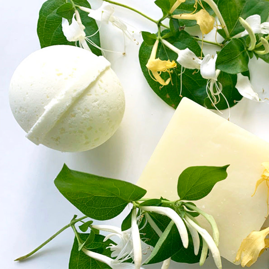 Honeysuckle Bath Bomb and Soap surrounded by honeysuckle plants