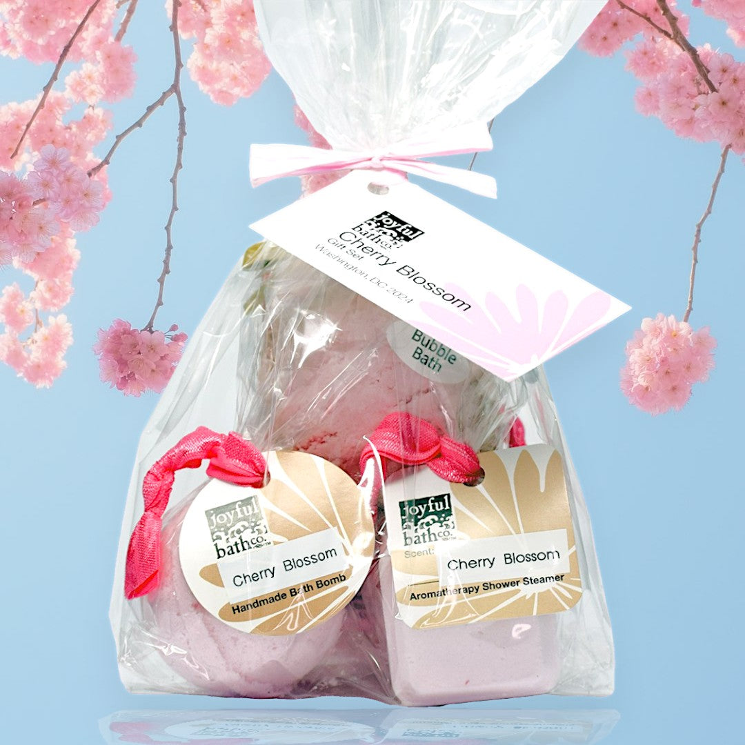 Cherry Blossoms Souvenir Set wrapped  with a pink paper bow over a sky blue background and cherry blossom branches