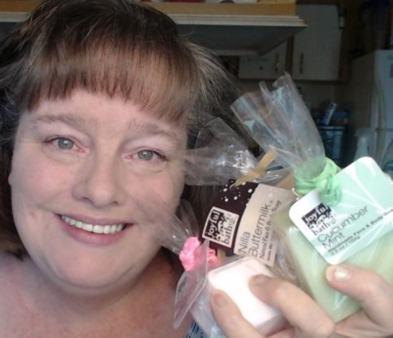 Female Customer smiling and holding Joyful Bath Co products with one hand