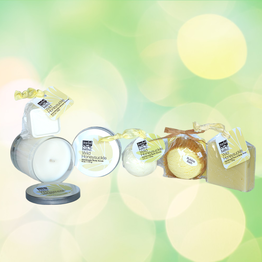 Bokeh image of the contents of the Total Bliss Gift Set, a candle, shower steamer, bath bomb, bubble bath scoop, and soap
