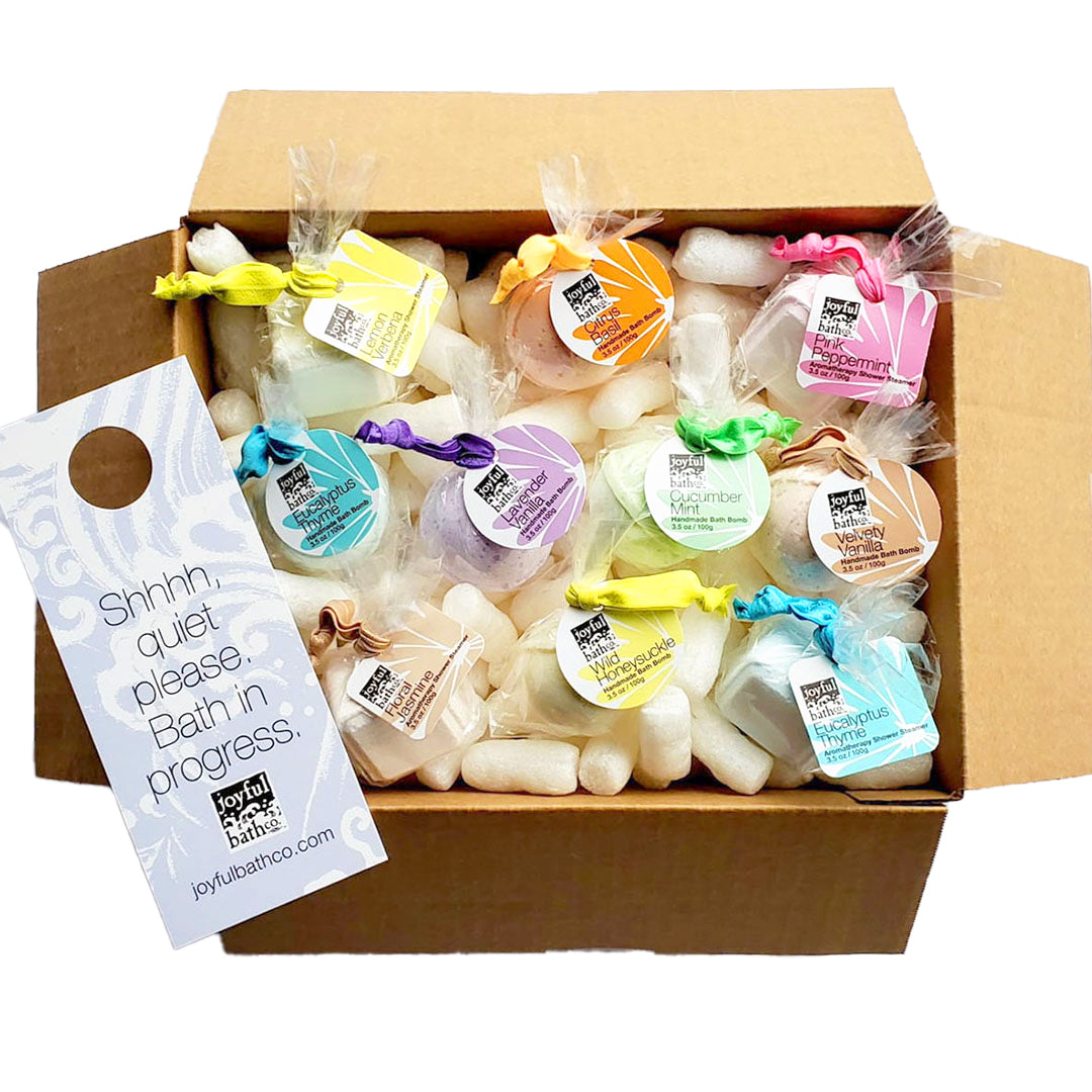 an open box filled with bath bombs and shower steamers atop a pile cornstarch peanuts