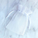 White mesh shower steamer bag with drawstring on marble background