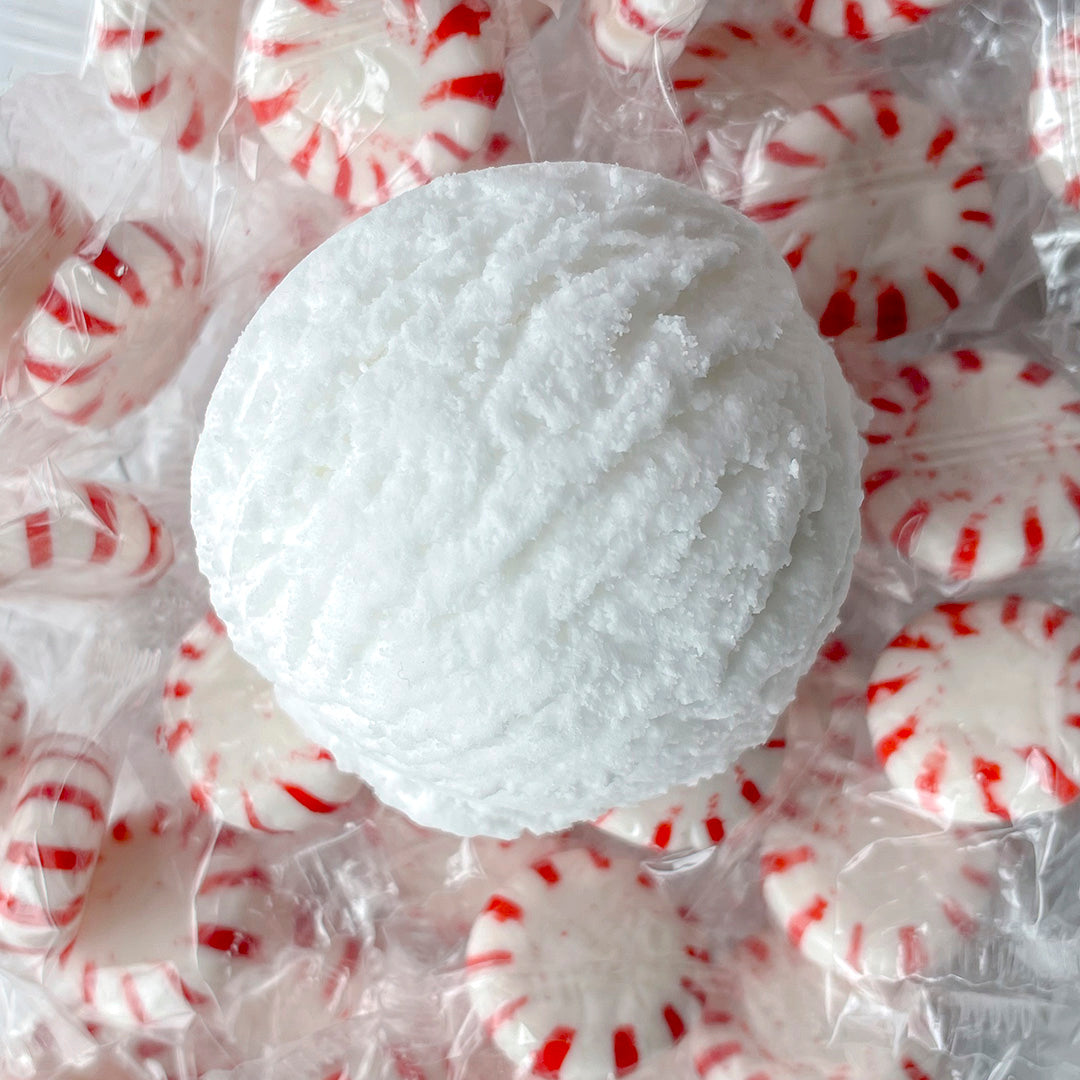 a white bubble bath scoop surrounded by peppermint candy