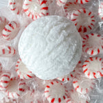 a white bubble bath scoop surrounded by peppermint candy