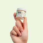 A hand holding up a jar of Hemp Balm on a light green background